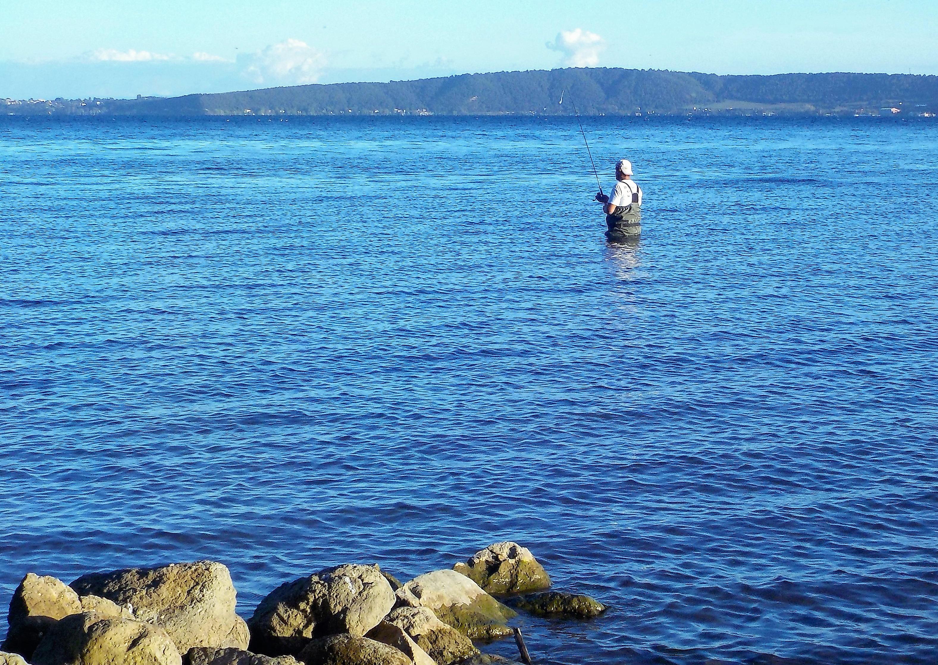 Pescador arremessando vara em lago calmo ao entardecer