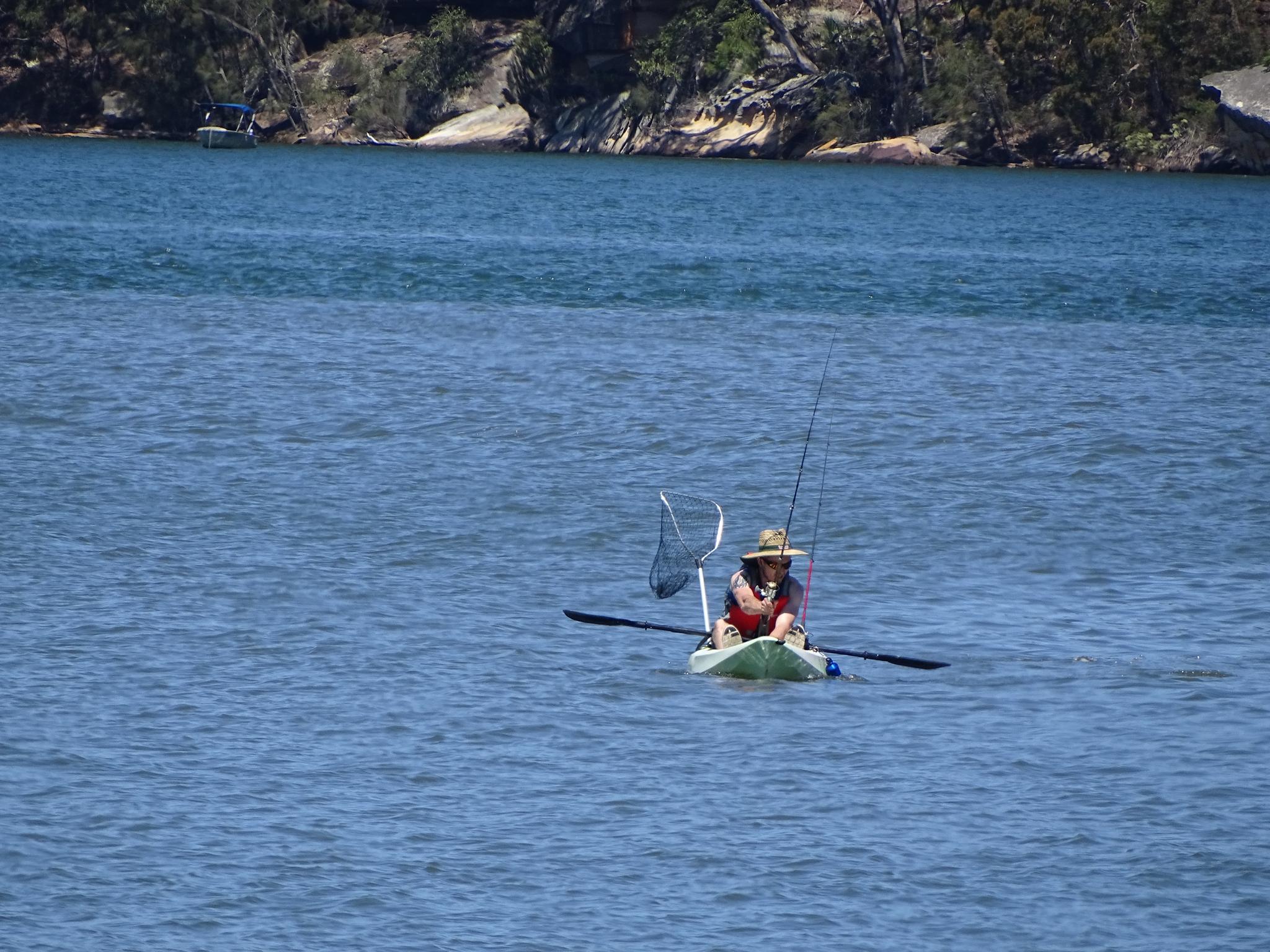 Pescador em caiaque sobre águas calmas com varas montadas